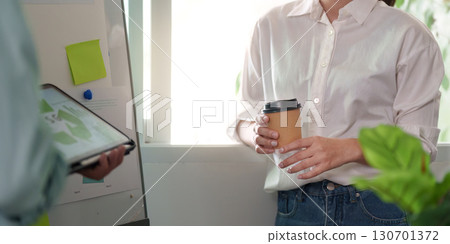 Businesswoman holding coffee during ESG discussion in a modern office. Businesswoman holding coffee during ESG discussion in a modern office. 130701372