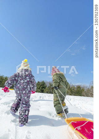 Back view of children climbing a hill in a winter park 130702309