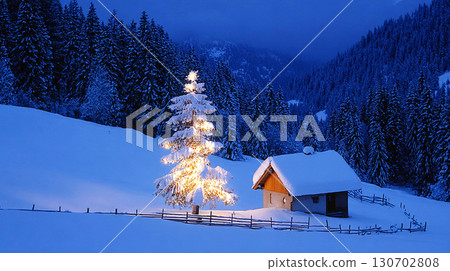 Cozy Winter Night with Illuminated Christmas Tree and Snow Covered Cabin in Forest 130702808