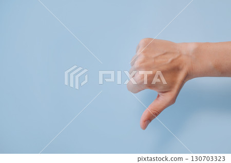 Hand showing thumbs down gesture on blue background with copy space, disapproval or dislike Hand showing thumbs down gesture on blue background with copy space, disapproval or dislike 130703323