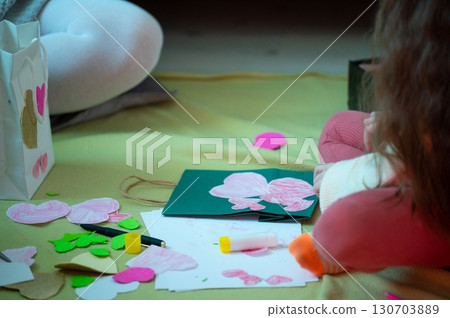 A child crafts heart-shaped decorations, showcasing creativity and festive preparation. A child crafts heart-shaped decorations, showcasing creativity and festive preparation. 130703889