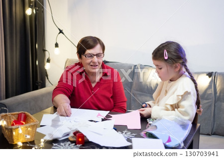 Grandmother and granddaughter crafting together, enjoying a creative moment filled with warmth and shared experience. 130703941