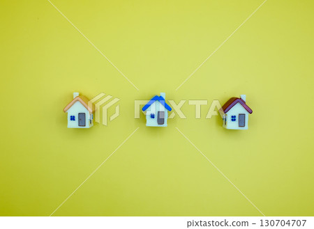 Miniature real estate houses in a row on yellow background with copy space 130704707