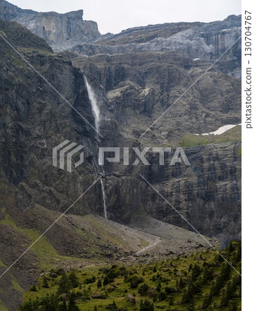 Flowing waterfall cascading down rugged cliffs of Cirque de Gavarnie in the Pyrenees, showcasing Flowing waterfall cascading down rugged cliffs of Cirque de Gavarnie in the Pyrenees, showcasing 130704767