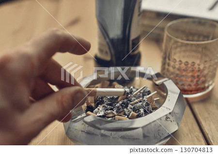 A hand holding a smoking tobacco cigarette. A hand holding a smoking tobacco cigarette. The concept of alcoholism, tobaccoism, and addictive behavior. 130704813