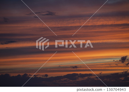 Sky transforms with vibrant hues during a stunning sunrise over the horizon, illuminating the clouds 130704943