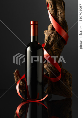 Bottle of red wine and old weathered snag with red satin ribbon. Bottle of red wine and old weathered snag with red satin ribbon. 130704967