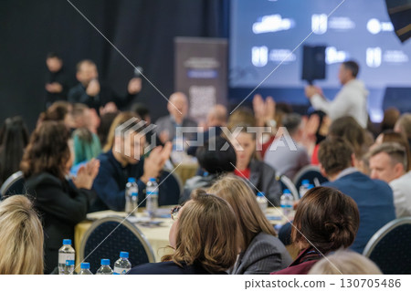 Business professionals attending a formal conference at a large venue 130705486