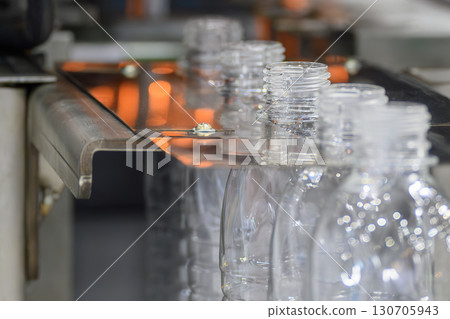 The drinking water bottles on the conveyor belt after blow mold machine. 130705943