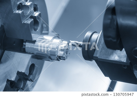 The CNC lathe machine drilling process on metal shaft parts by center drill tool in the blue tone. The CNC lathe machine drilling process on metal shaft parts by center drill tool in the blue tone. 130705947