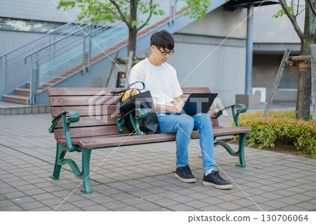 一名男子在長椅上操作電腦 130706064