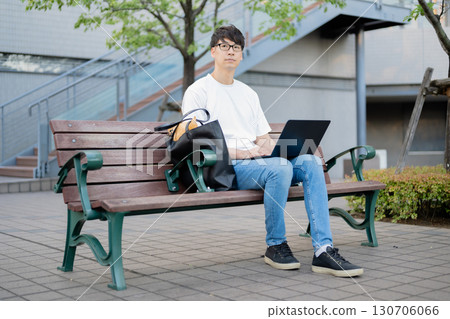 一名男子在長椅上操作電腦 130706066