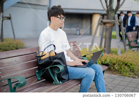 一名男子在長椅上操作電腦 130706067