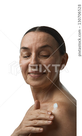 Mature woman applying cream on shoulder with calm smile Mature woman applying cream on shoulder with calm smile 130706528