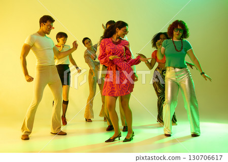 Friends enjoying retro dance in yellow neon spotlight with joy Friends enjoying retro dance in yellow neon spotlight with joy 130706617