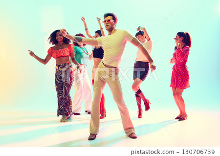 Group of stylish young people dancing together in colorful studio light Group of stylish young people dancing together in colorful studio light 130706739