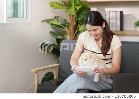 Woman enjoying quality time with cat while using smartphone at home 130706800
