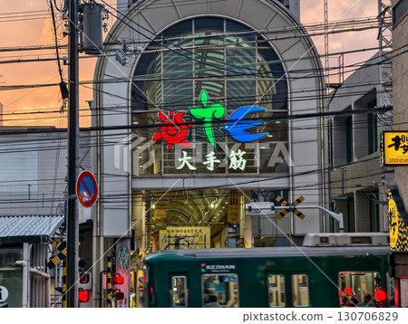 The entrance to the arcade of Fushimi Ote-suji Shopping Street at dusk, with a Keihan train passing through. Kyoto City, Kyoto Prefecture, Japan The entrance to the arcade of Fushimi Ote-suji Shopping Street at dusk, with a Keihan train passing through. Kyoto City, Kyoto Prefecture, Japan 130706829