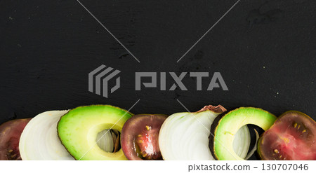 chopped vegetables black tomatoes, avocado and onions against black stone board chopped vegetables black tomatoes, avocado and onions against black stone board 130707046