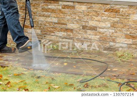 Man cleaning street with high pressure power washer, washing stone garden paths. High quality photo Man cleaning street with high pressure power washer, washing stone garden paths. High quality photo 130707214