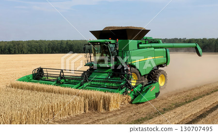 Modern Green Combine Harvester Working on a Wheat Field During Harvest Season. Modern Green Combine Harvester Working on a Wheat Field During Harvest Season. 130707495