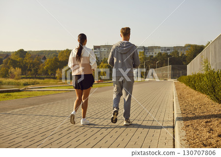 Back view of young couple wearing sportswear jogging in the park having sport workout. Back view of young couple wearing sportswear jogging in the park having sport workout. 130707806