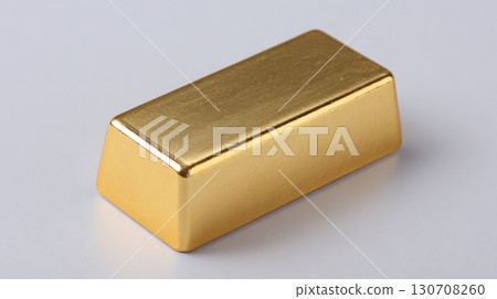 Shiny gold bar on a light gray surface, reflecting light. Investment and wealth concepts. Rich golden hue. Minimalist composition. 130708260