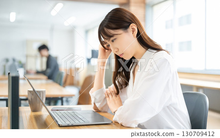 一位女商人一邊用電腦一邊思考 130709412