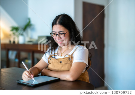 Portrait asian freelance people business female wearing glasses stylish hipste Draw or taking note on digital tablet with electronic pen for browsing internet, chatting and blogging in coffee shop. 130709732