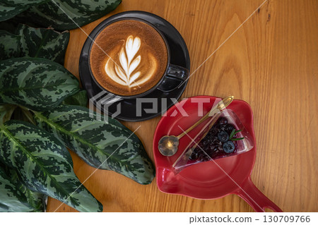 Hot coffee latte with latte art milk foam in cup and Blueberry Cake on wood desk on top view. As breakfast In a coffee shop at the cafe,during business work concept Hot coffee latte with latte art milk foam in cup and Blueberry Cake on wood desk on top view. As breakfast In a coffee shop at the cafe,during business work concept 130709766