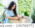 a portrait of beautiful happy asian woman traveler wearing a beautiful blue dress lifestyle enjoying holding using smartphone cellphone casual working in sitting coffee shop restaurant background 130709771