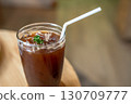 Close-up of Iced Black americano in a glass cup mug on  wood desk office desk in coffee shop at the cafe in garden,during business work concept 130709777