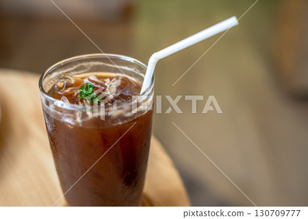 Close-up of Iced Black americano in a glass cup mug on  wood desk office desk in coffee shop at the cafe in garden,during business work concept 130709777