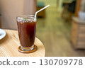 Close-up of Iced Black americano in a glass cup mug on  wood desk office desk in coffee shop at the cafe in garden,during business work concept 130709778