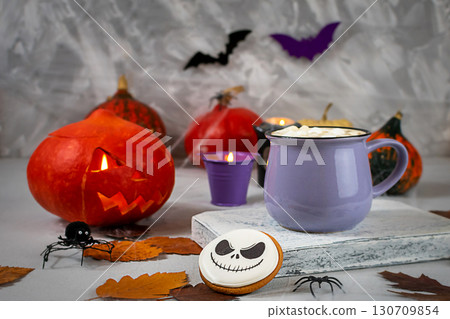 Pumpkin jack-o'-lantern and hot cocoa on a spooky Halloween-themed table Pumpkin jack-o'-lantern and hot cocoa on a spooky Halloween-themed table 130709854