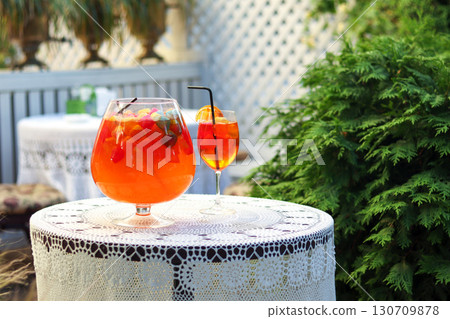 Elegant outdoor table setting with vibrant drinks and lush greenery Elegant outdoor table setting with vibrant drinks and lush greenery 130709878