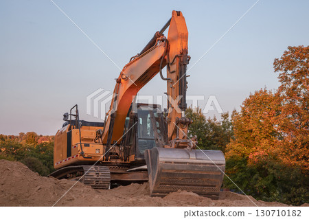 Orange Excavator on Dirt Pile at Construction Site Orange Excavator on Dirt Pile at Construction Site 130710182
