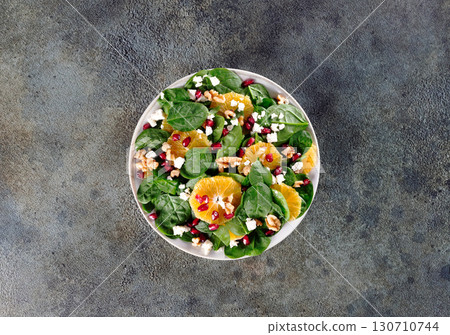 Green salad with oranges, pomegranate, walnuts and feta cheese. Vegetarian salad. Top view. Green salad with oranges, pomegranate, walnuts and feta cheese. Vegetarian salad. Top view. 130710744