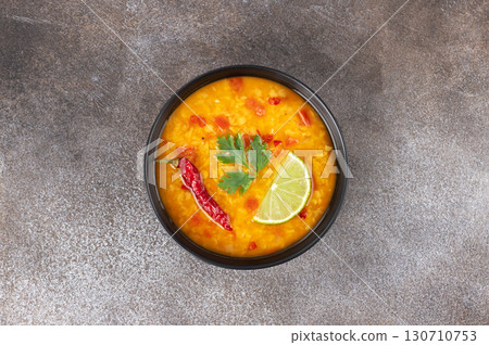 Indian dal soup with red lentils, spices, fresh cilantro and lime on a gray background. Indian food Indian dal soup with red lentils, spices, fresh cilantro and lime on a gray background. Indian food 130710753