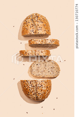Freshly sliced multigrain bread with sesame and flax seeds on a bright beige background with shadow. 130710774
