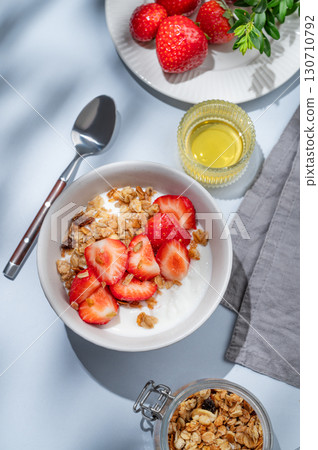 Granola or muesli with natural greek yogurt, strawberry and honey in a bowl on a blue background 130710792