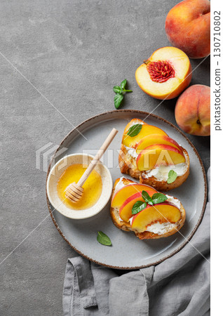 Flat lay of toast bruschetta with peach, nectarine, cream cheese or ricotta and honey on a plate 130710802
