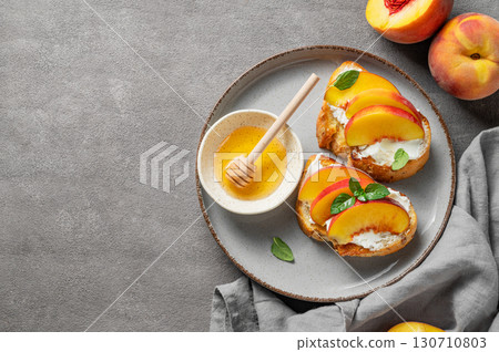 Toast bruschetta with peach, nectarine, cream cheese or ricotta and honey on a plate  130710803