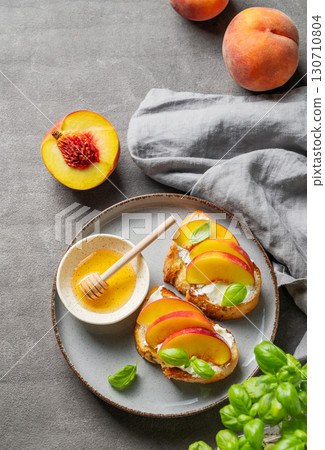 Toast bruschetta with peach, nectarine, cream cheese or ricotta and honey on a plate 130710804