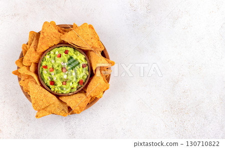 A bowl of guacamole with crispy nachos on a light background. Perfect for a party appetize. Mexican food. 130710822