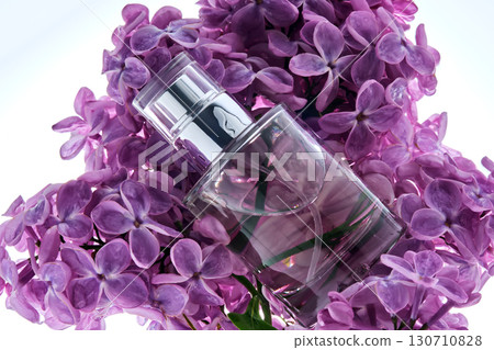 A bottle of perfume on a lilac branch in close-up. 130710828