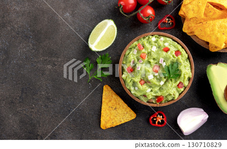 Mexican guacamole dip with avocado, tomatoes, chilli pepper, tortilla chips. Top view. Copy space Mexican guacamole dip with avocado, tomatoes, chilli pepper, tortilla chips. Top view. Copy space 130710829