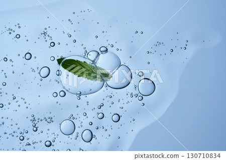 Beautiful texture of gel-like serum with a leaf on a blue background. Beautiful texture of gel-like serum with a leaf on a blue background. 130710834