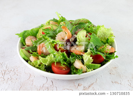 Shrimp salad with avocado, cherry tomatoes, green leaf mix salad and sesame seeds on a white background. Shrimp salad with avocado, cherry tomatoes, green leaf mix salad and sesame seeds on a white background. 130710835