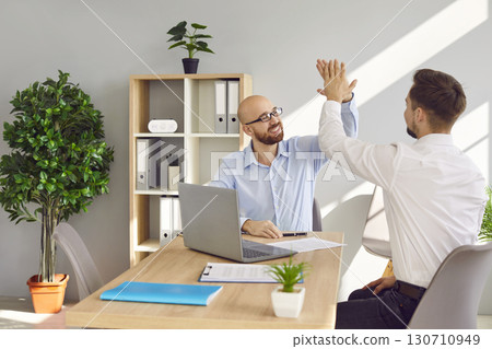 Two friendly male colleagues compliting task and giving high five 130710949